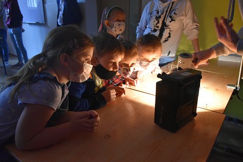 Grupa dzieci skupionych wokół przyrządu. 