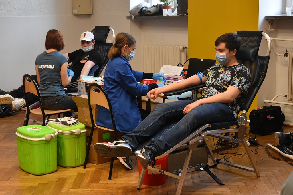 Dwóch uczniów siedzi na fotelach obok nich dwie panie pobierające krew.