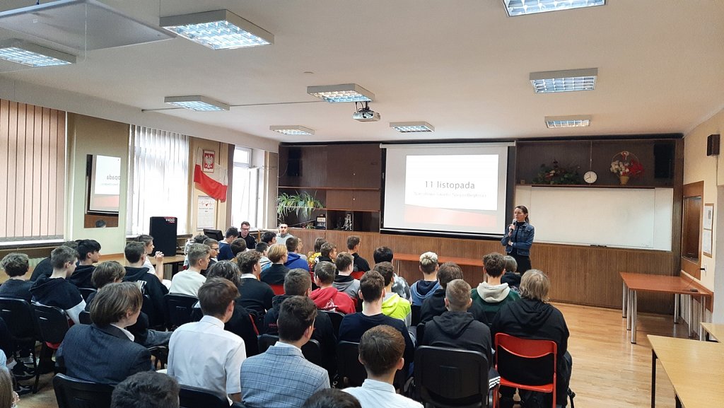 Sala konferencyjna. Na ekranie wyświetlona prezentacja. Uczniowie siedzą i słuchają przemówienia p. Dyrektor. 