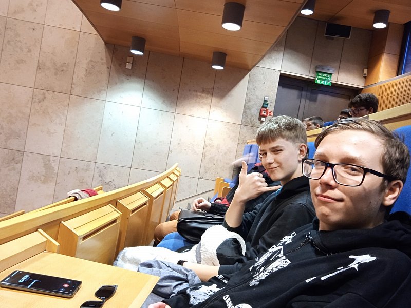 Dwóch uczniów w sali audytoryjnej podczas wykładu. 